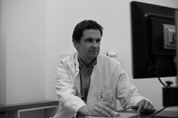 Herr Dr. med. Niclas Wedemeyer sitzt mit wei&szlig;em Arztkittel am Computer und liest etwas nach